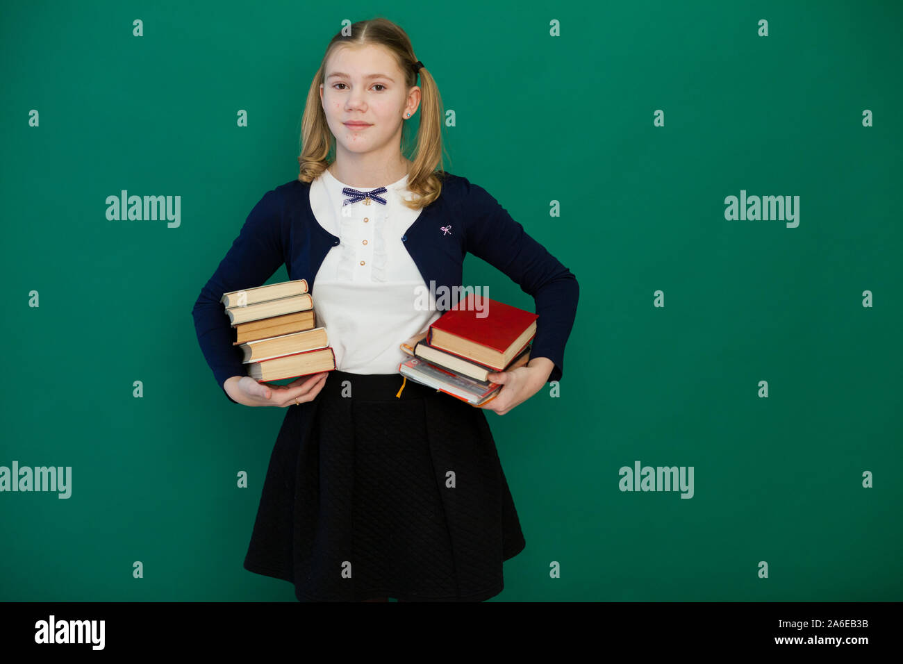 schoolgirl girl stands with books in the classroom Stock Photo - Alamy