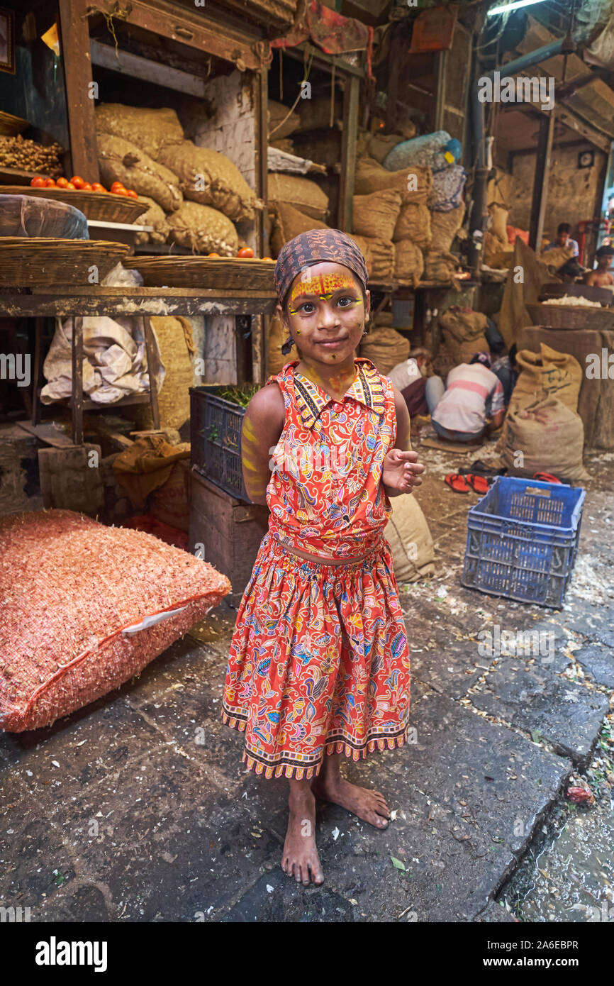 A colorfully dressed girl from Karnataka, S.India, with religious markings on her forehead, sent out by her mother to beg in a market in Mumbai, India Stock Photo