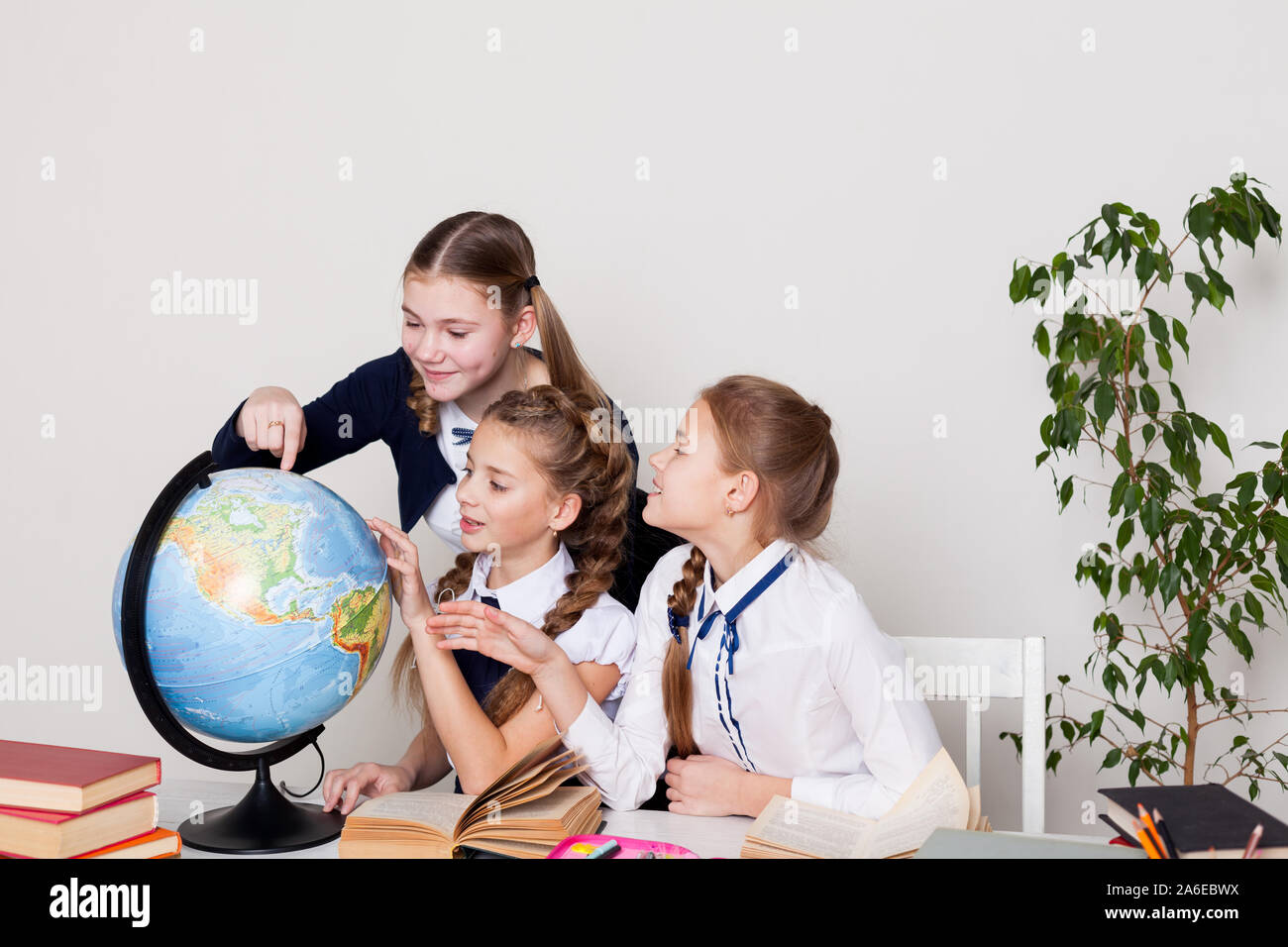 three girls watching the globe in geography class Stock Photo - Alamy