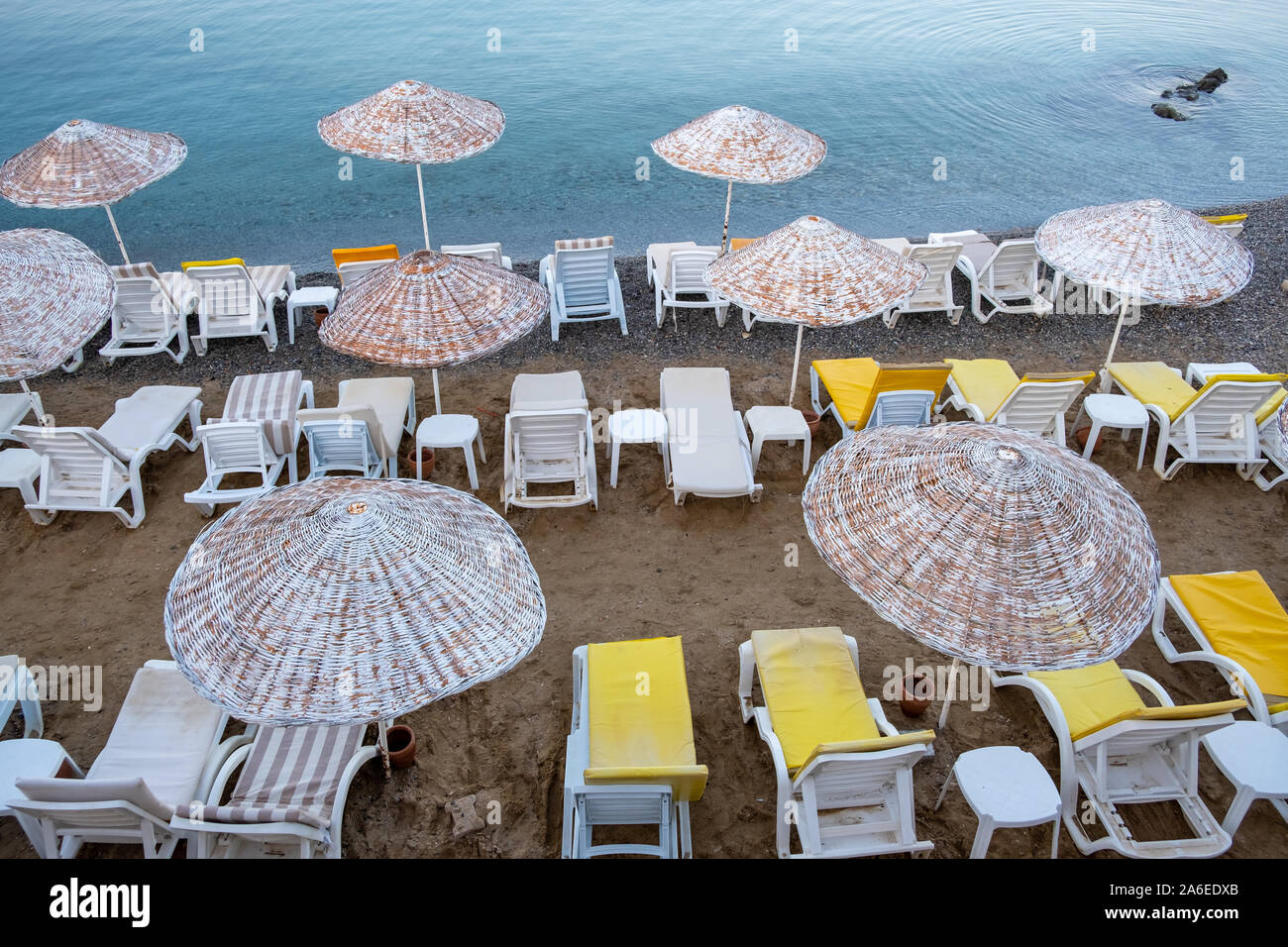 Beautiful view of the empty beach with umbrellas on the background of sunrise over the sea. Turkey, Bodrum, Stock Photo