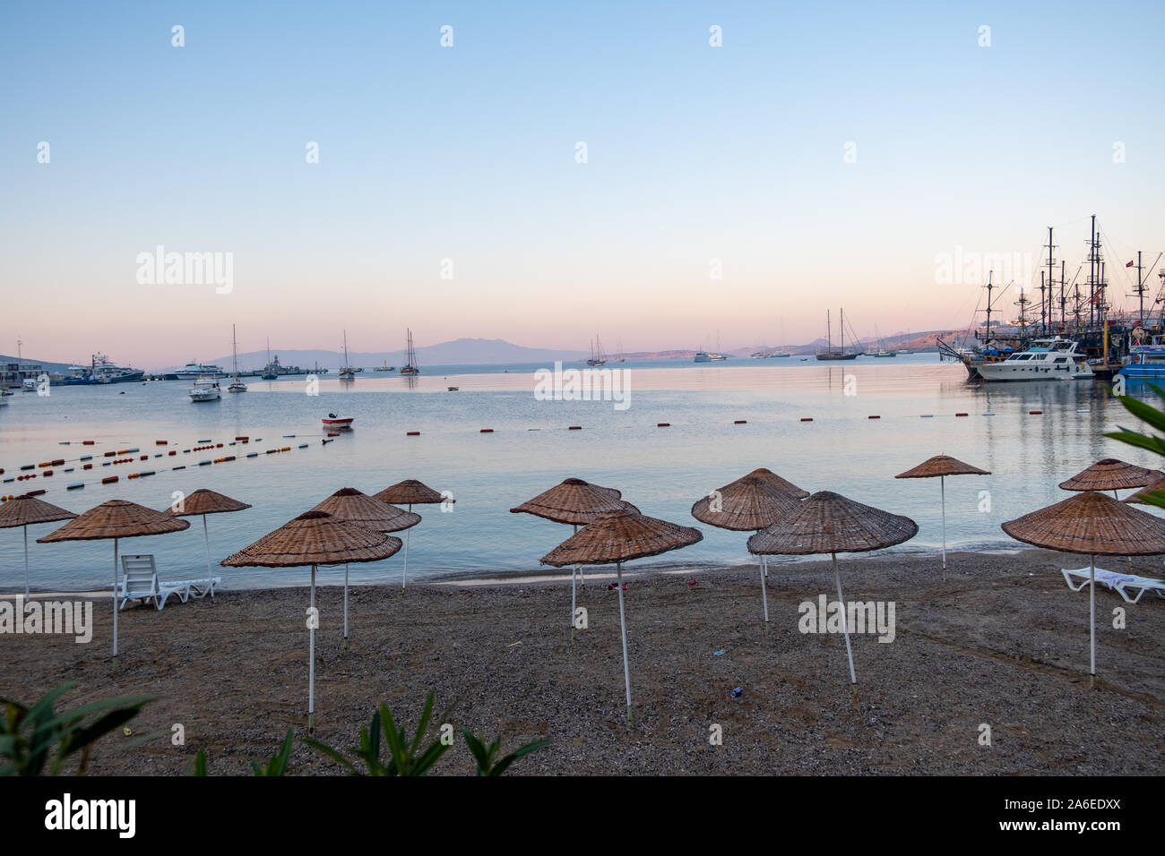 Beautiful view of the empty beach with umbrellas on the background of sunrise over the sea. Turkey, Bodrum, Stock Photo