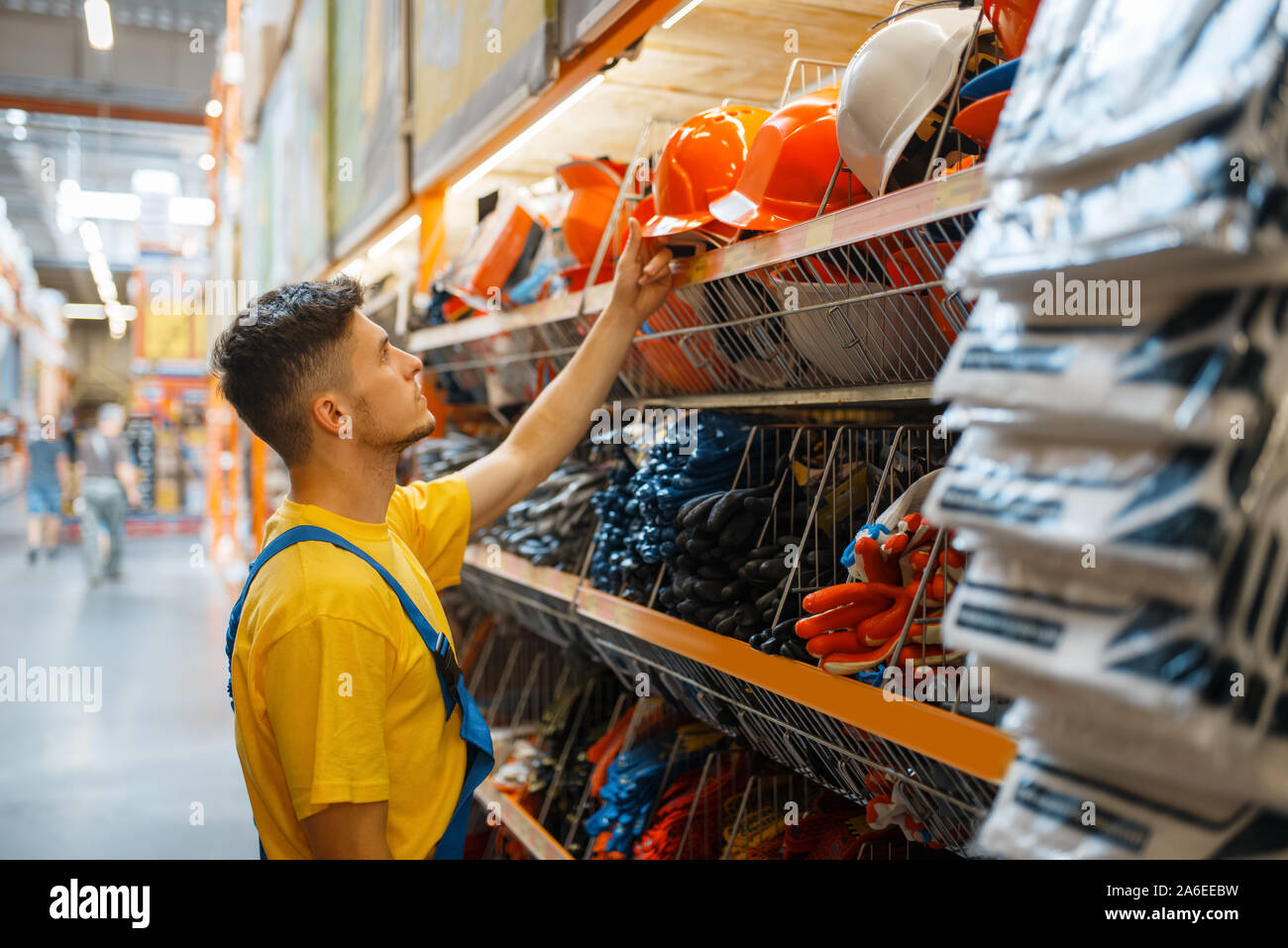 Male builder choosing helmet in hardware store Stock Photo