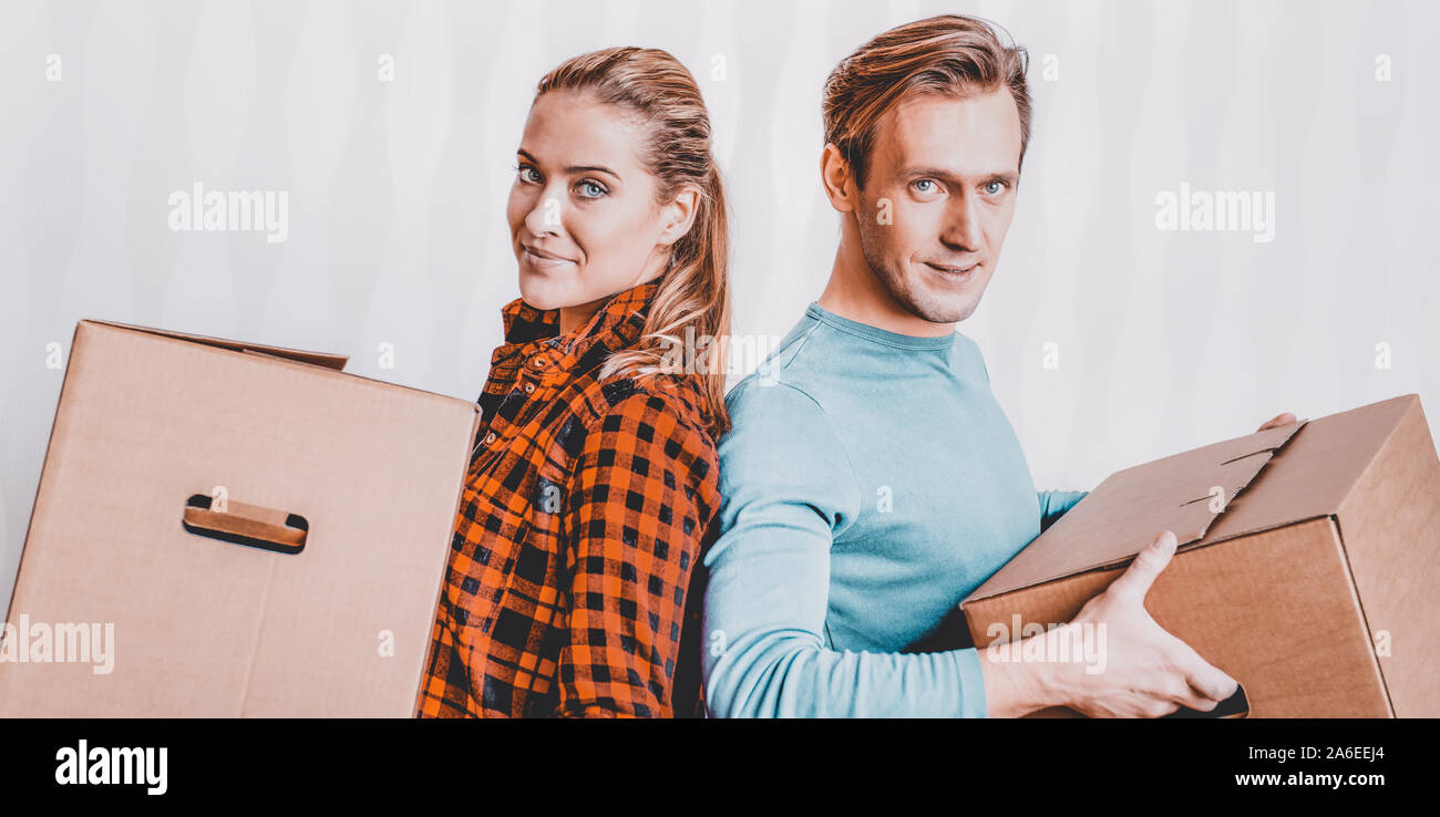 Married couple carrying boxes. Moving to new house. Renting estate