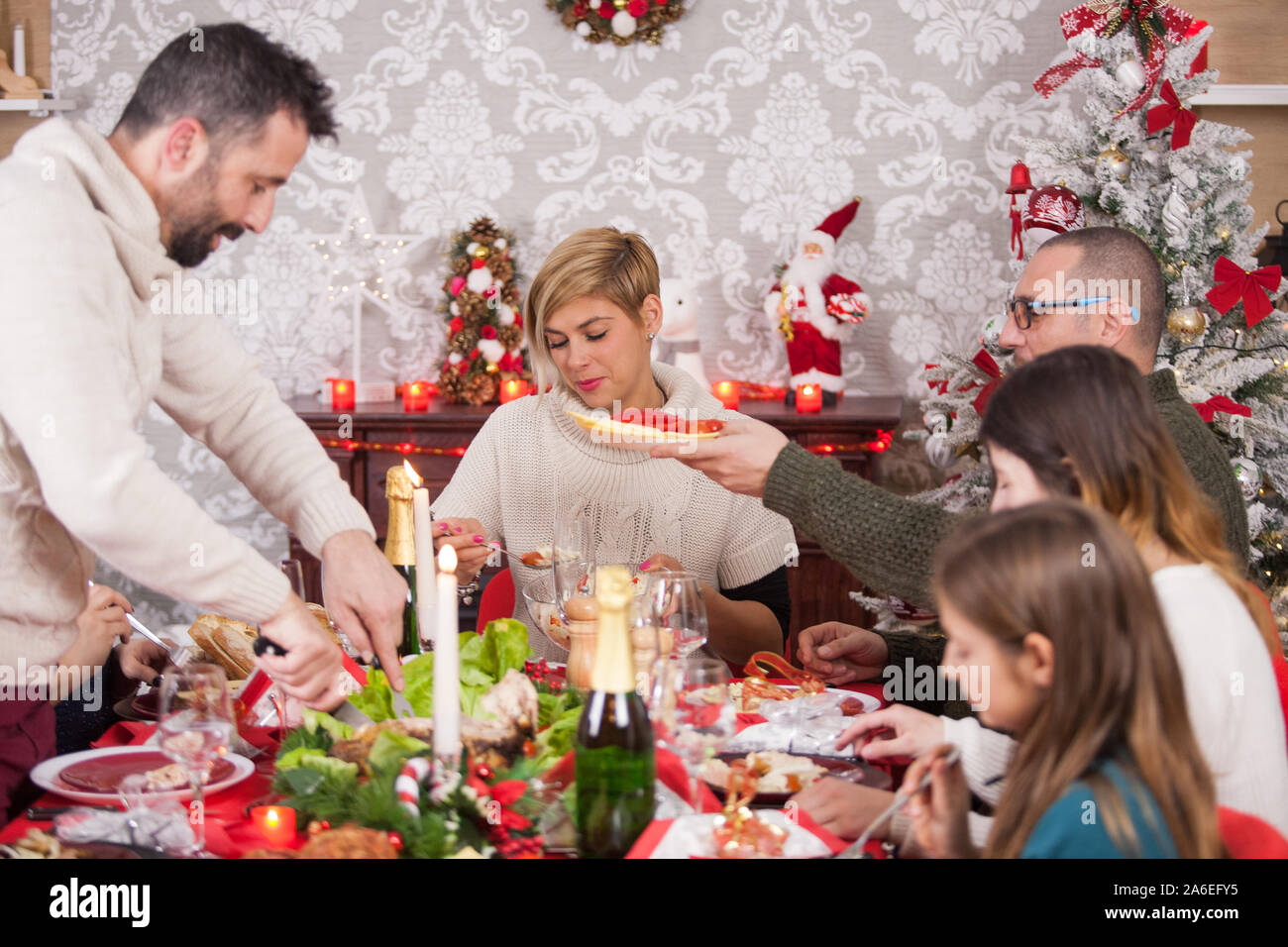 Uncle cutting turkey for family on christmas dinner. Beautiful home decoration for christmas. Beautiful family on christmas dinner. Happines around the table on christmas eve. Stock Photo