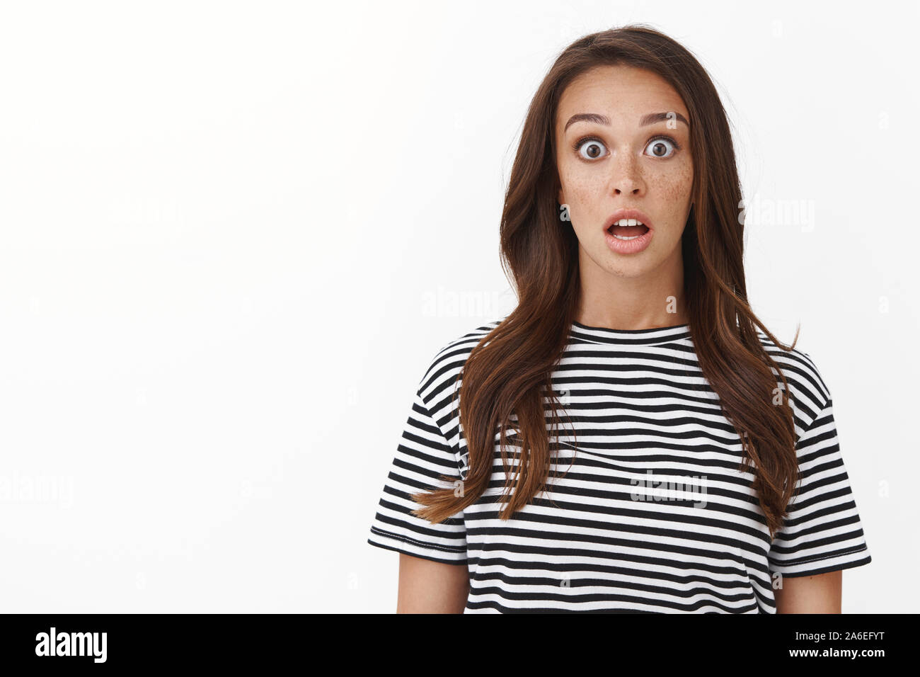 Surprised speechless cute brunette girl in striped t shirt drop jaw