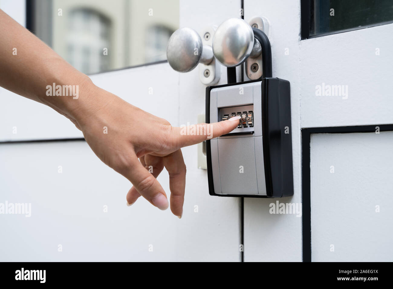 Woman Using Key Safe To Retrieve Keys From House Stock Photo