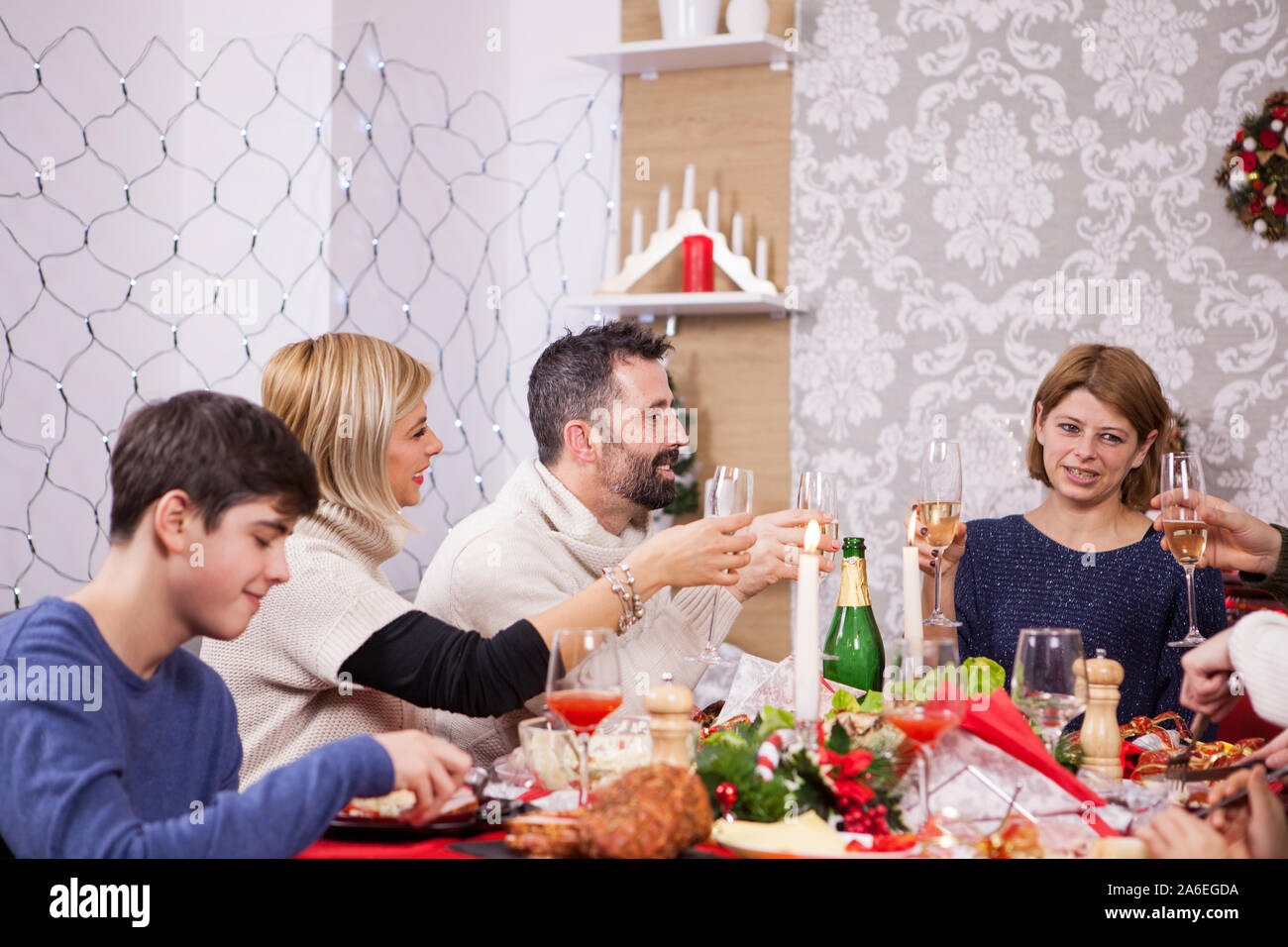 Family celebrating christmas in a cozy apartment. Christmas decoration. Children sitting around the table. Stock Photo