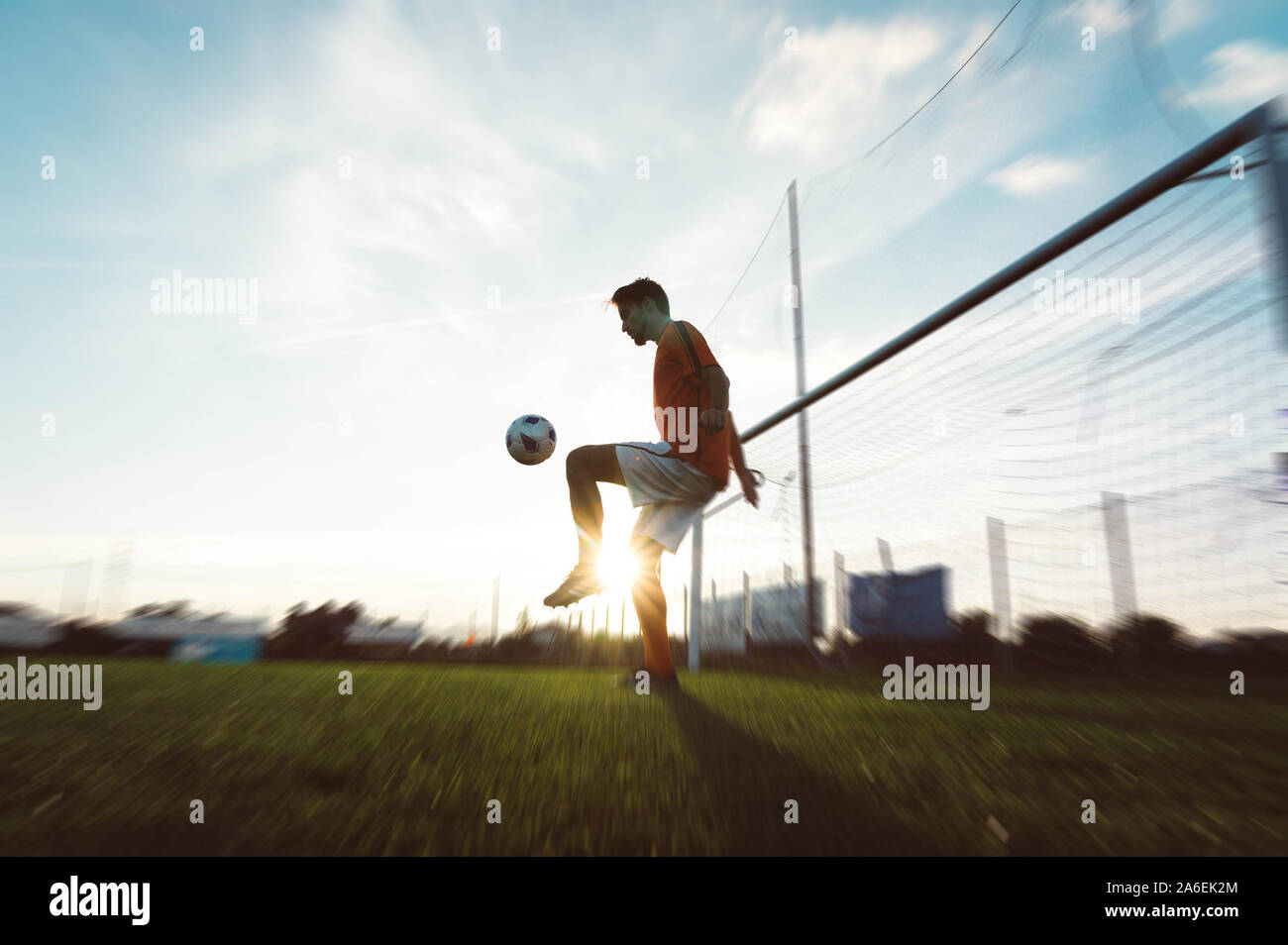 Soccer player is training alone at the stadium at sunset. Concept about