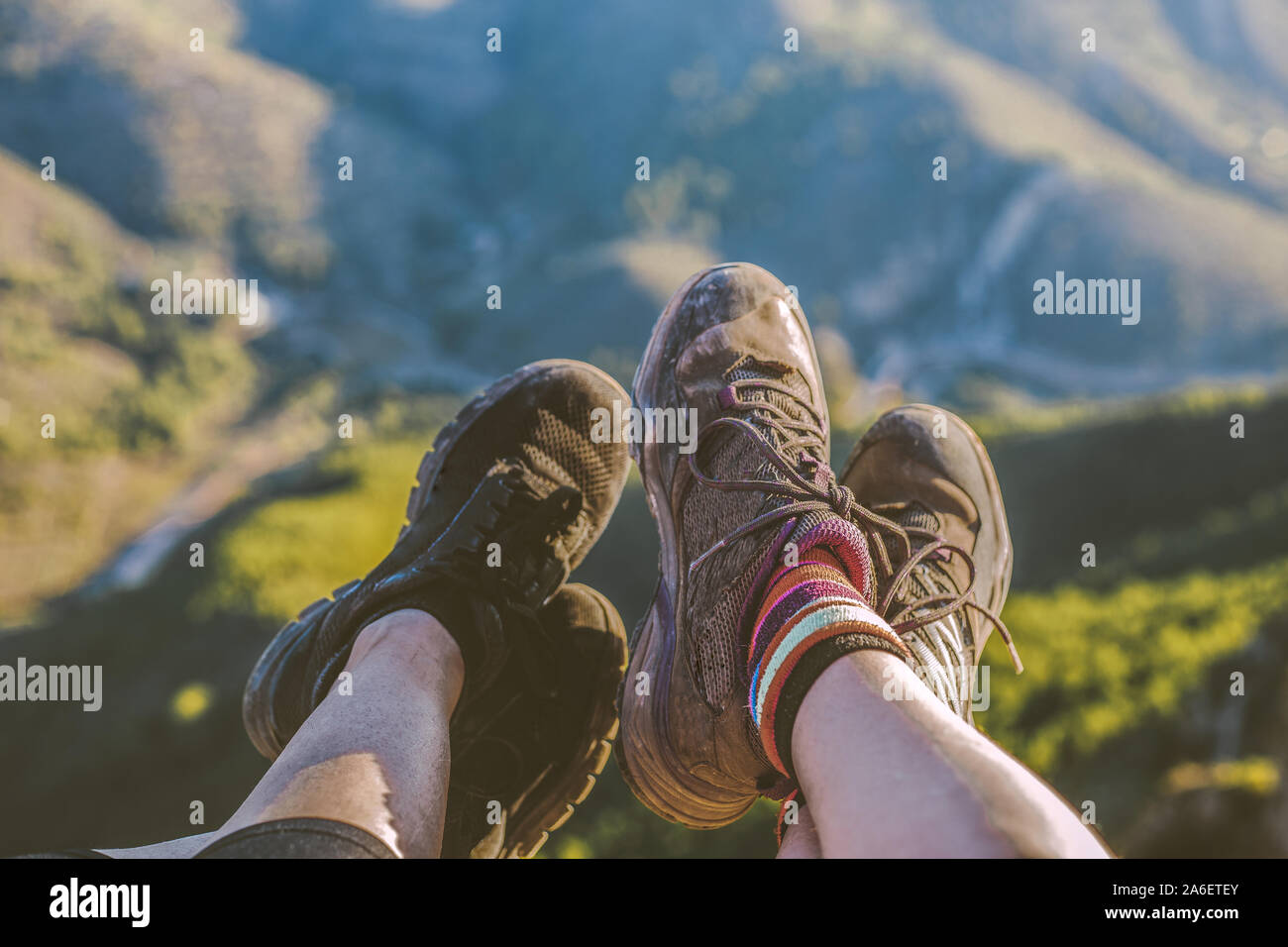 Point of view angle of two women´s feet, together on the edge of a cliff, wearing trainers - Two girl friends lying down with their sports shoes on ov Stock Photo