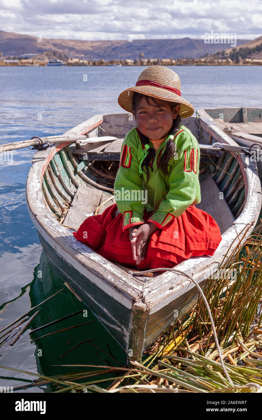 A portrait of a young girl sitting in a boat on a floating Uro Island in Lake Titicaca, Puno, Peru. Stock Photo