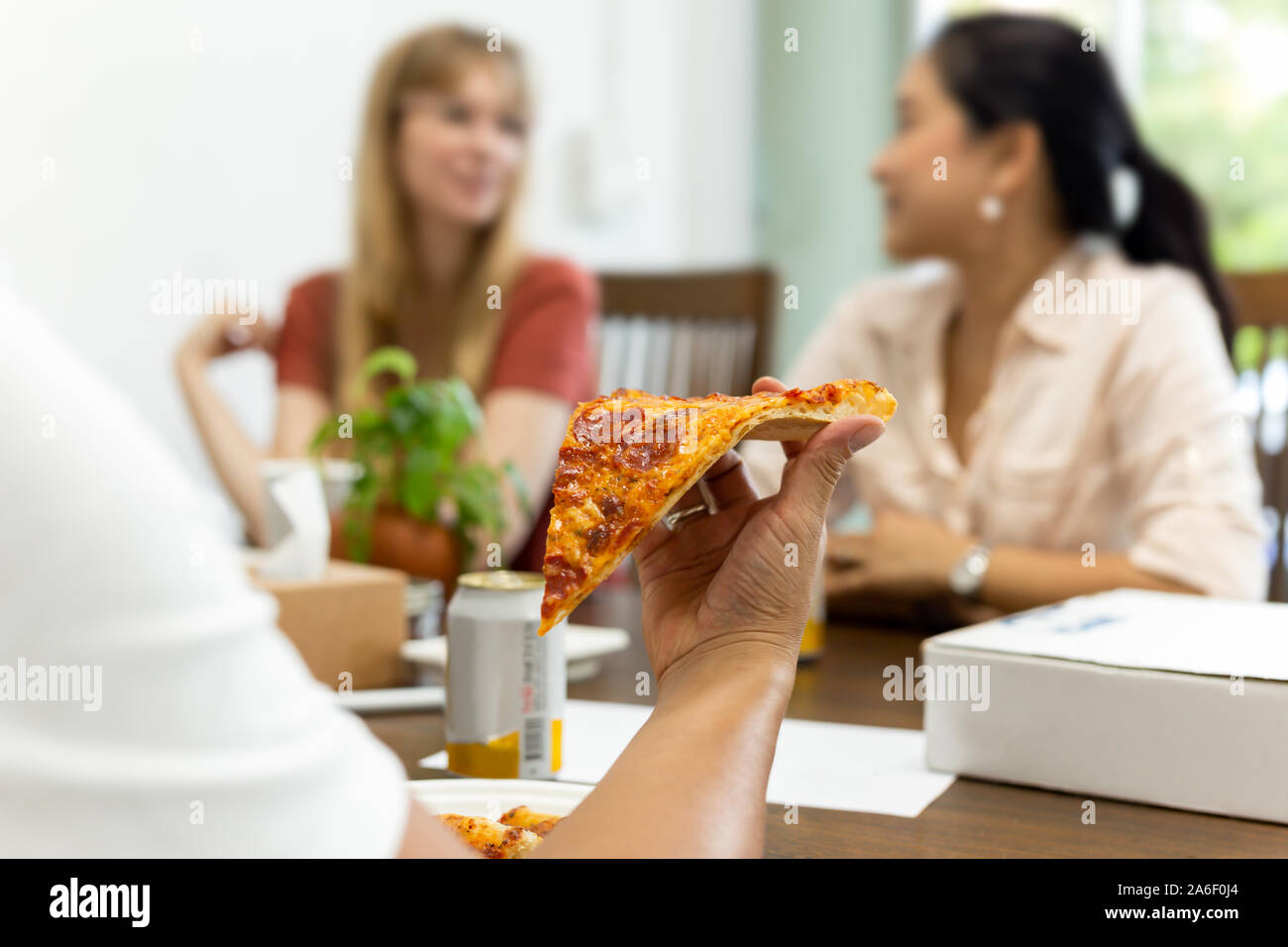 Friends eating pizza during meeting at pizzeria together. Stock Photo