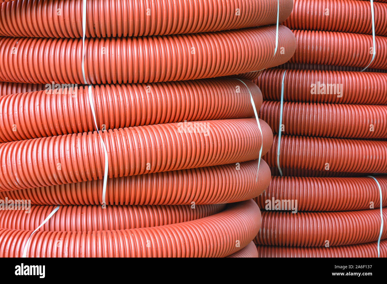Coils of new red plastic pipe with rain drops. Red plastic tubing for