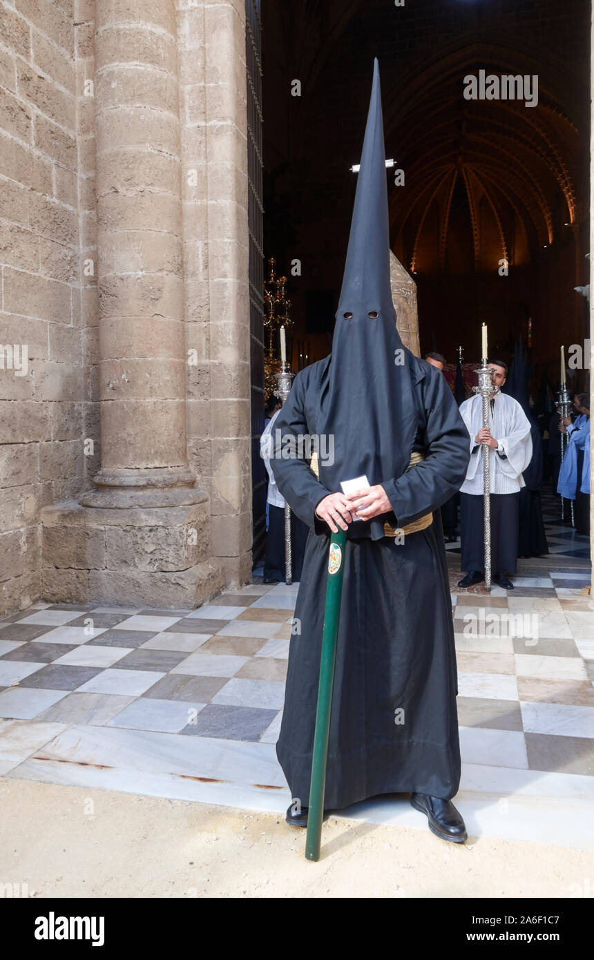 A member of a religious brotherhood wearing a penitential robe and conical hood for a Semana Santa procession in Jerez, Andalusia, Spain. Stock Photo