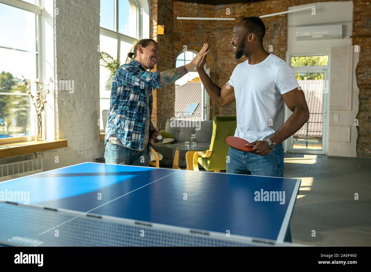 Young men playing table tennis in workplace, having fun. Friends in casual  clothes play ping pong together at sunny day. Concept of leisure activity,  sport, friendship, teambuilding, teamwork Stock Photo - Alamy
