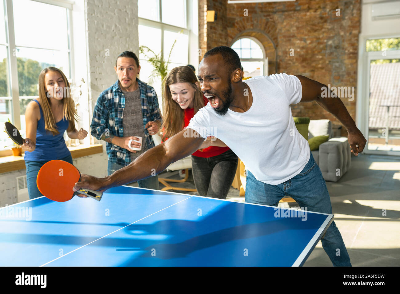 Young people playing table tennis in workplace, having fun. Friends in  casual clothes play ping pong together at sunny day. Concept of leisure  activity, sport, friendship, teambuilding, teamwork Stock Photo - Alamy