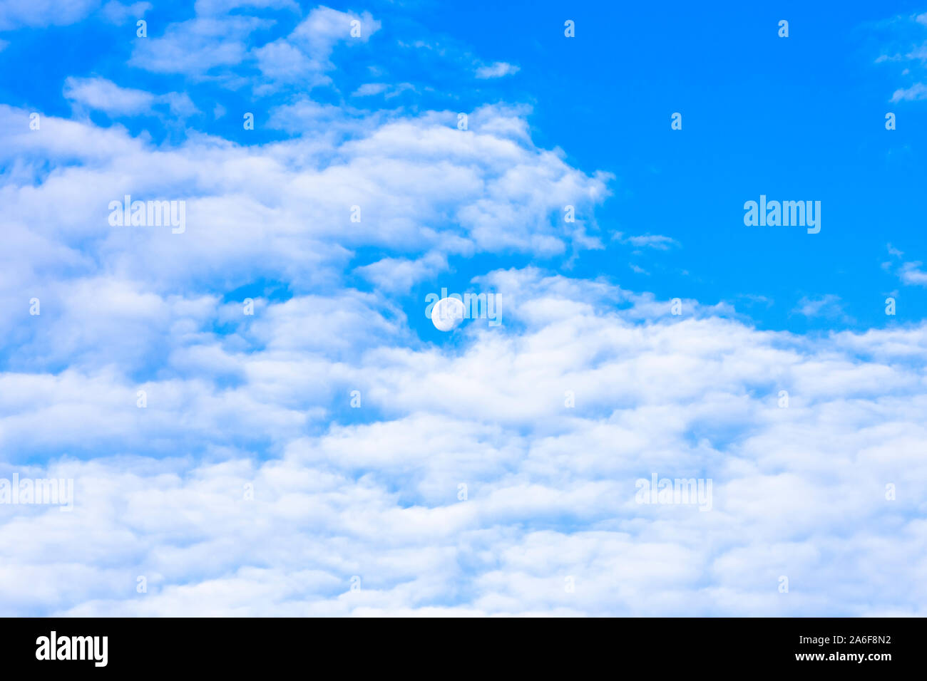 waning moon in blue sky, daylight, daytime, white clouds Stock Photo