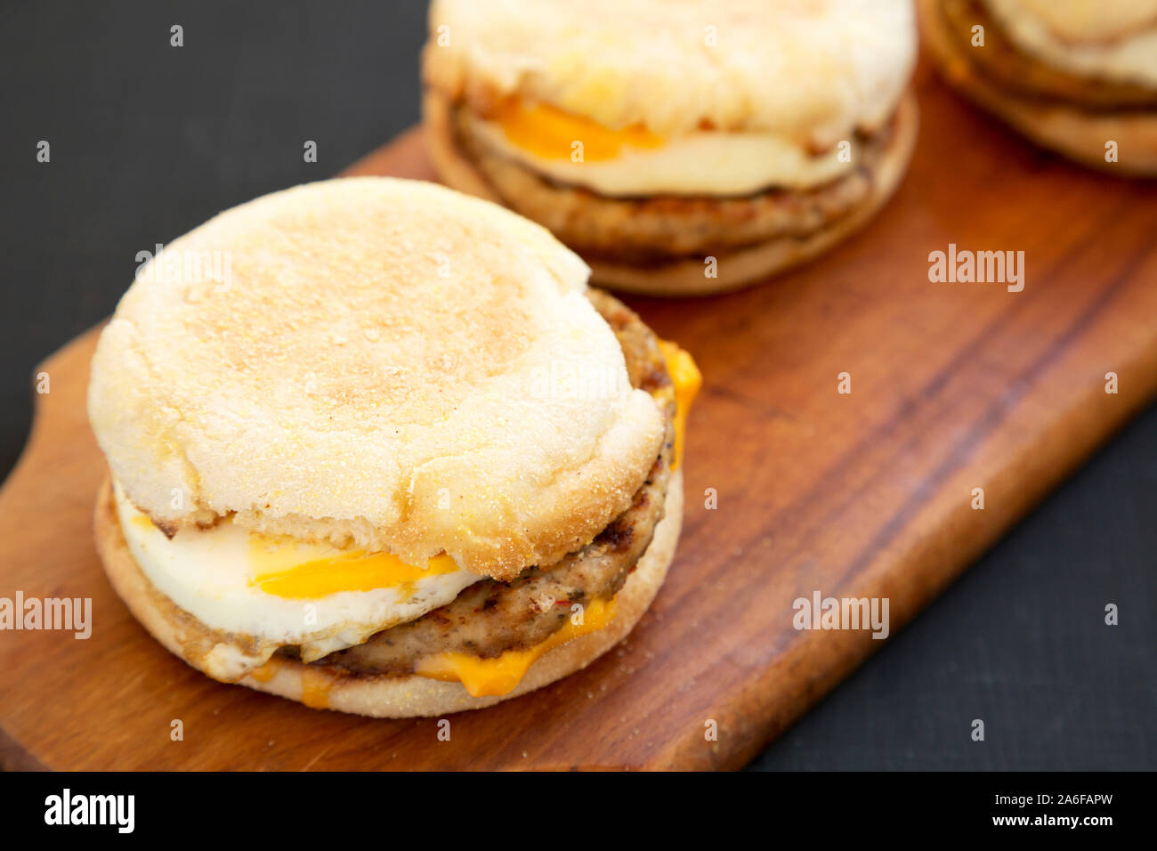 Homemade pork roll egg sandwich on a rustic wooden board on a black
