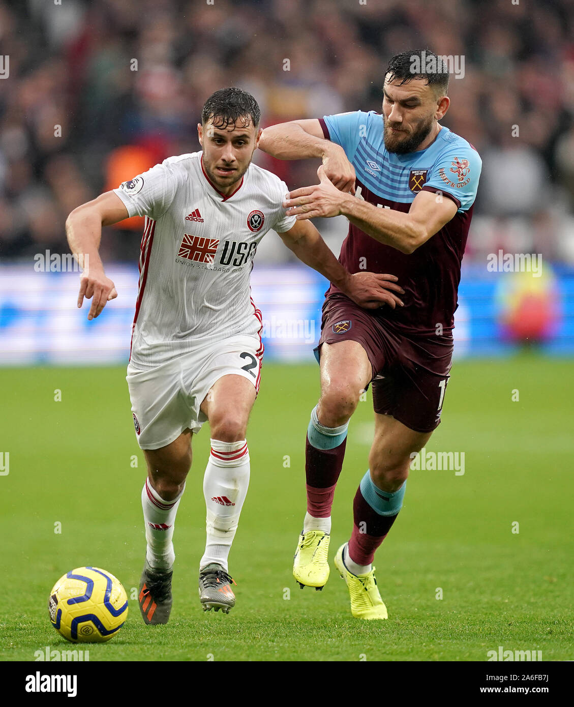 Sheffield United's George Baldock (left) and West Ham United's Robert Snodgrass battle for the ball during the Premier League match at London Stadium. Stock Photo