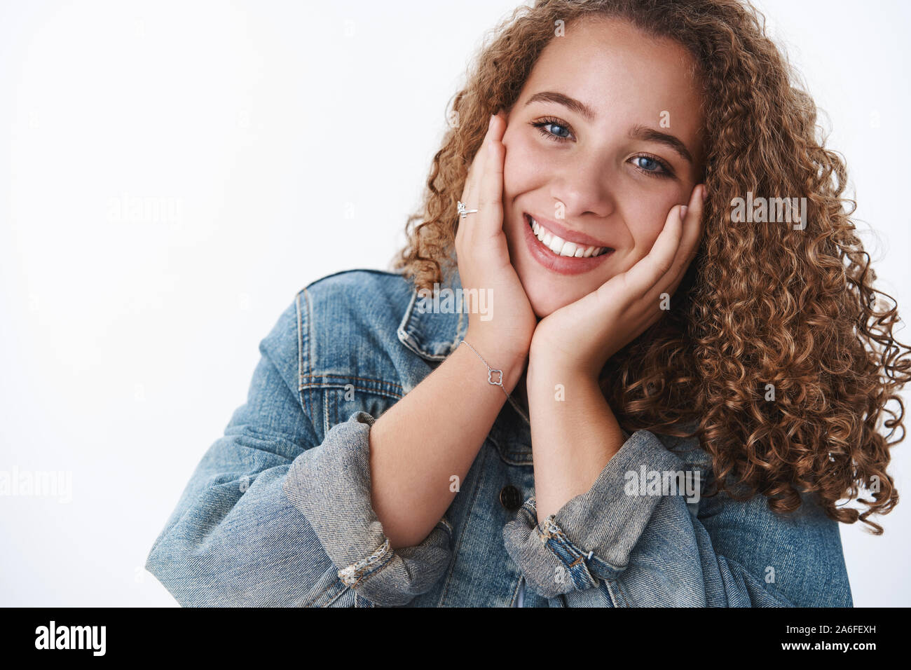 Close-up tender happy delighted excited charming curly-haired chubby girlfriend feeling upbeat touching cheeks joyfully blushing tilting head feeling Stock Photo