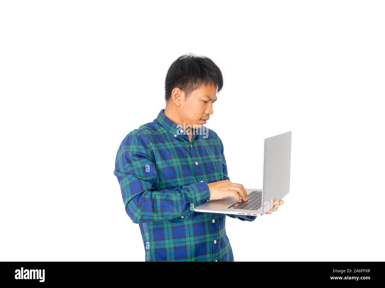The Asian untidy man in blue plaid shirt is holding a laptop on his left hand. Stock Photo