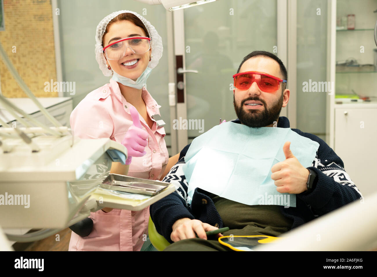 Young female dentist doctor and patient smiling at camera at the dental