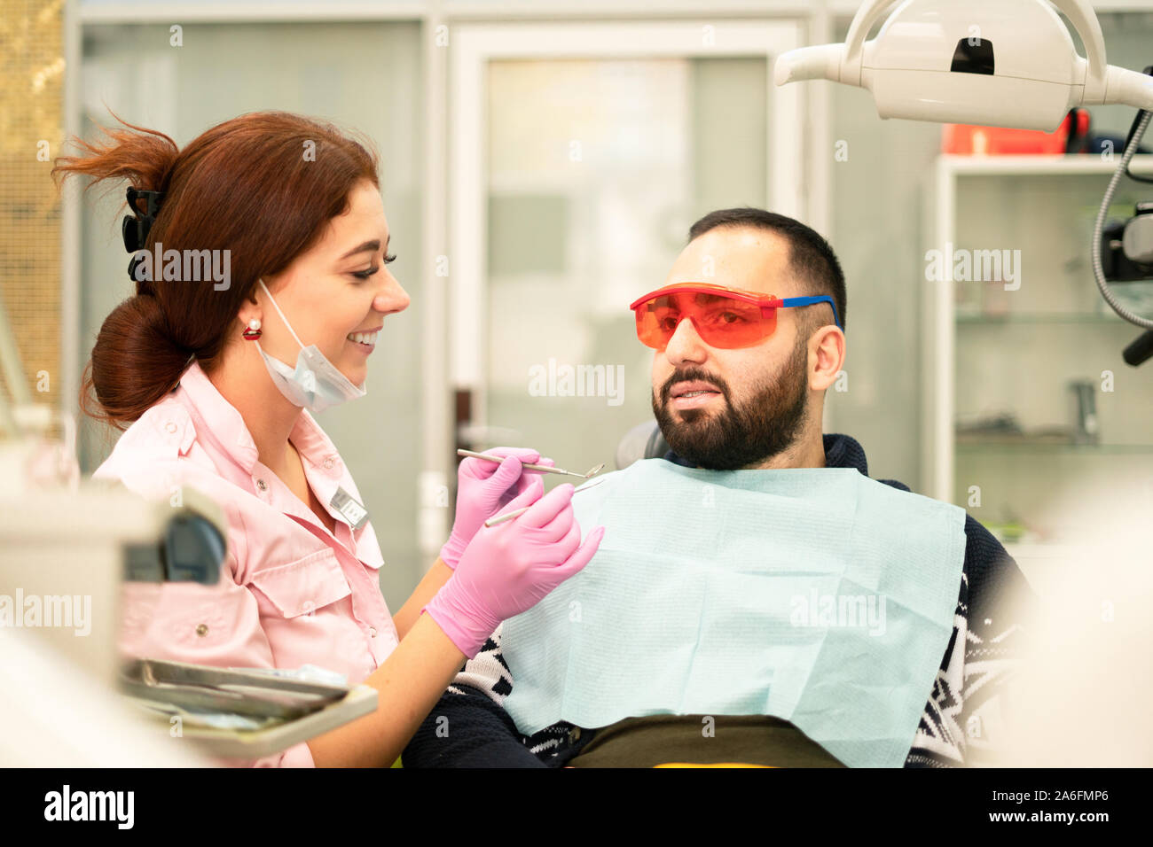 Young female dentist doctor and patient smiling at camera at the dental