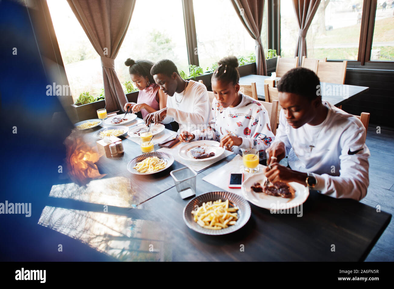 Happy african friends sitting, chatting in cafe and eat food. Group of ...