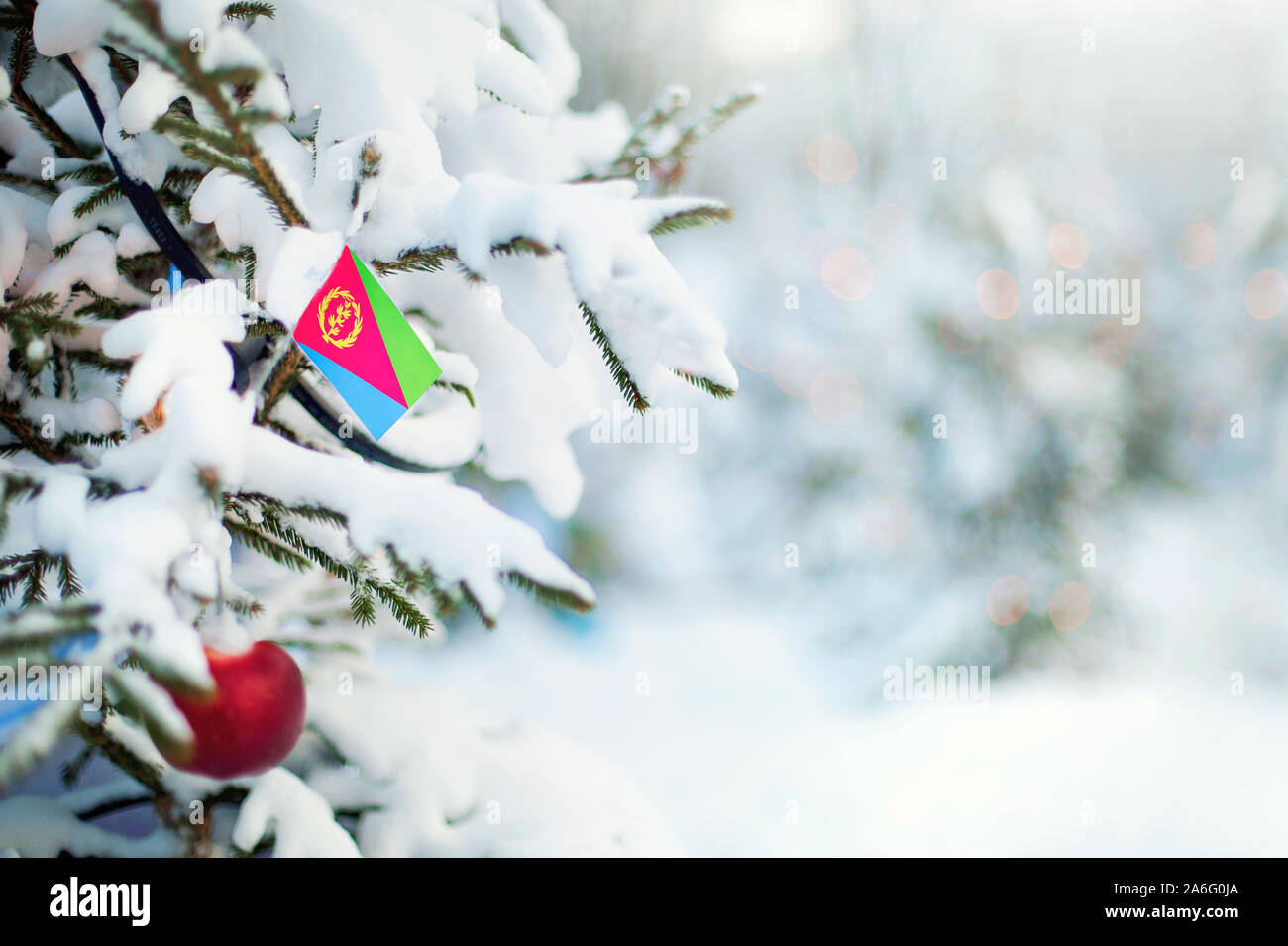 Christmas Eritrea. Xmas tree covered with snow, decorations and a flag