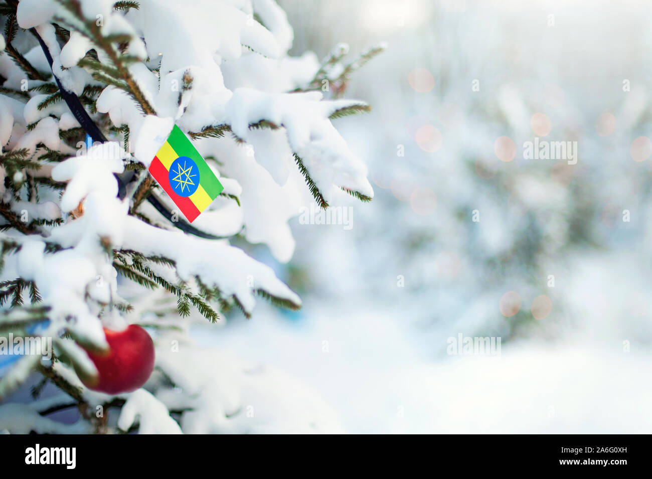 Christmas Ethiopia. Xmas tree covered with snow, decorations and a flag