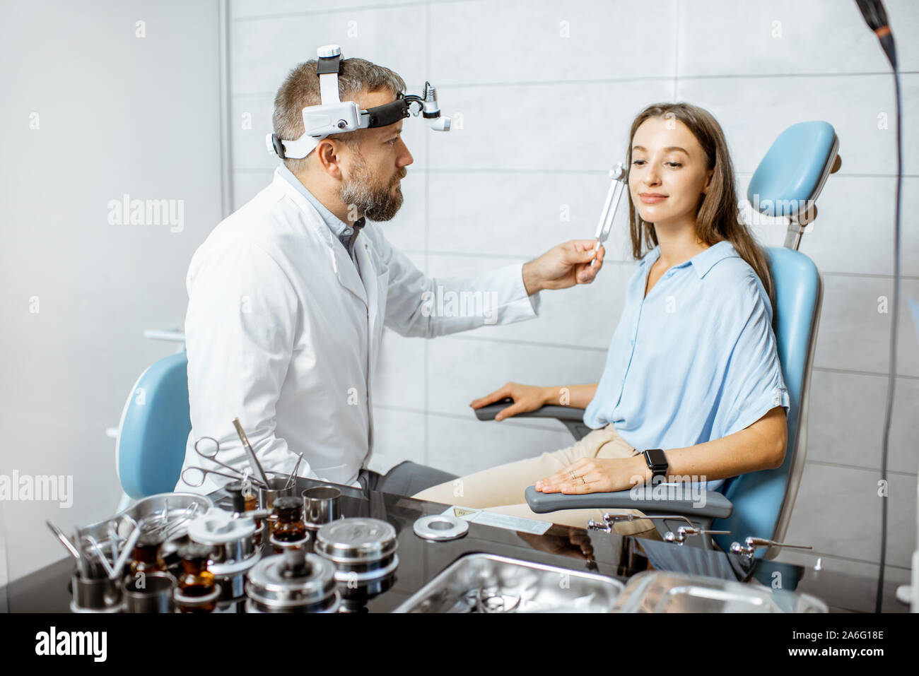 Senior otolaryngologist examining ears with ENT tuning fork for a young