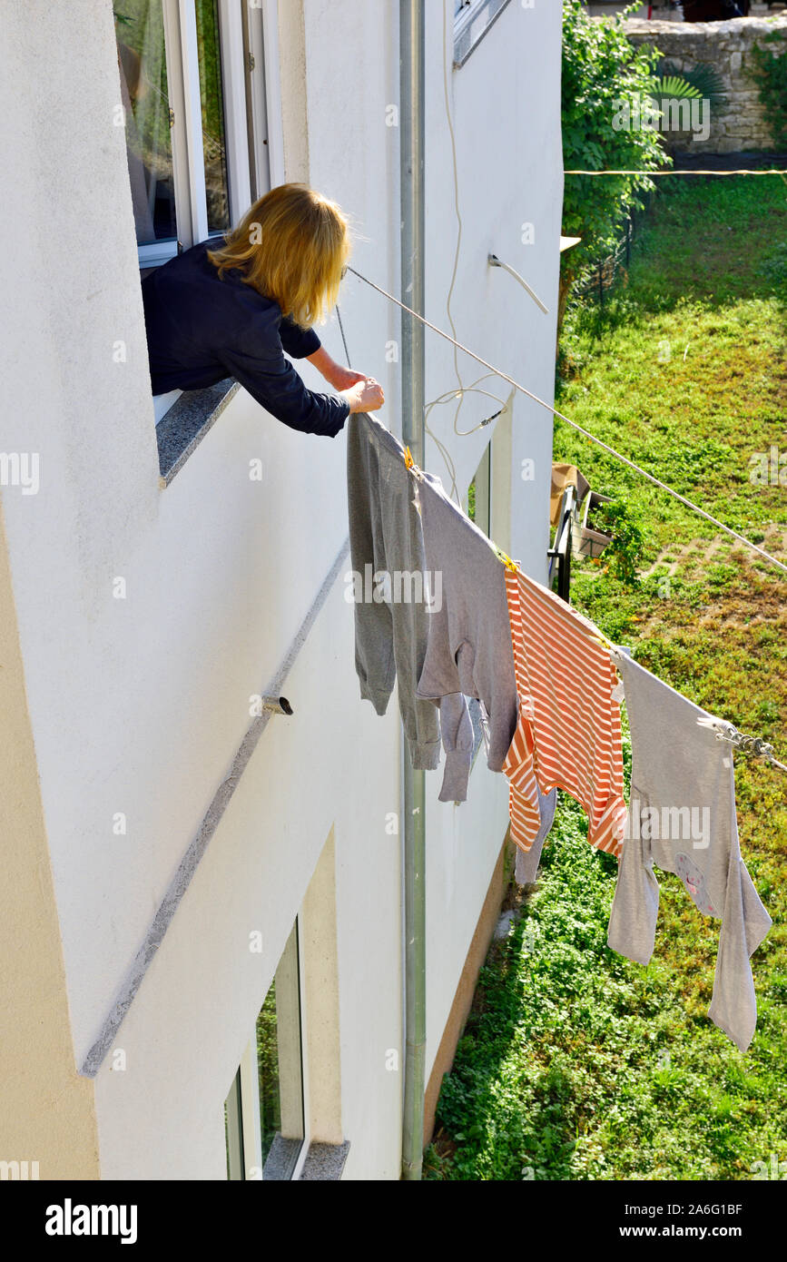 Woman hanging laundry out to dry in fresh air, the energy efficient way of drying washing Stock Photo