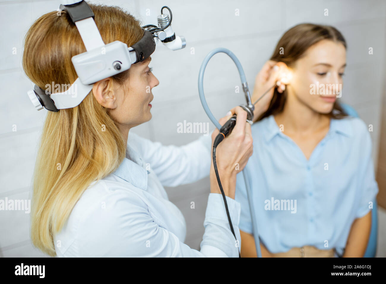 Senior otolaryngologist making endoscopic examination of an ear for a
