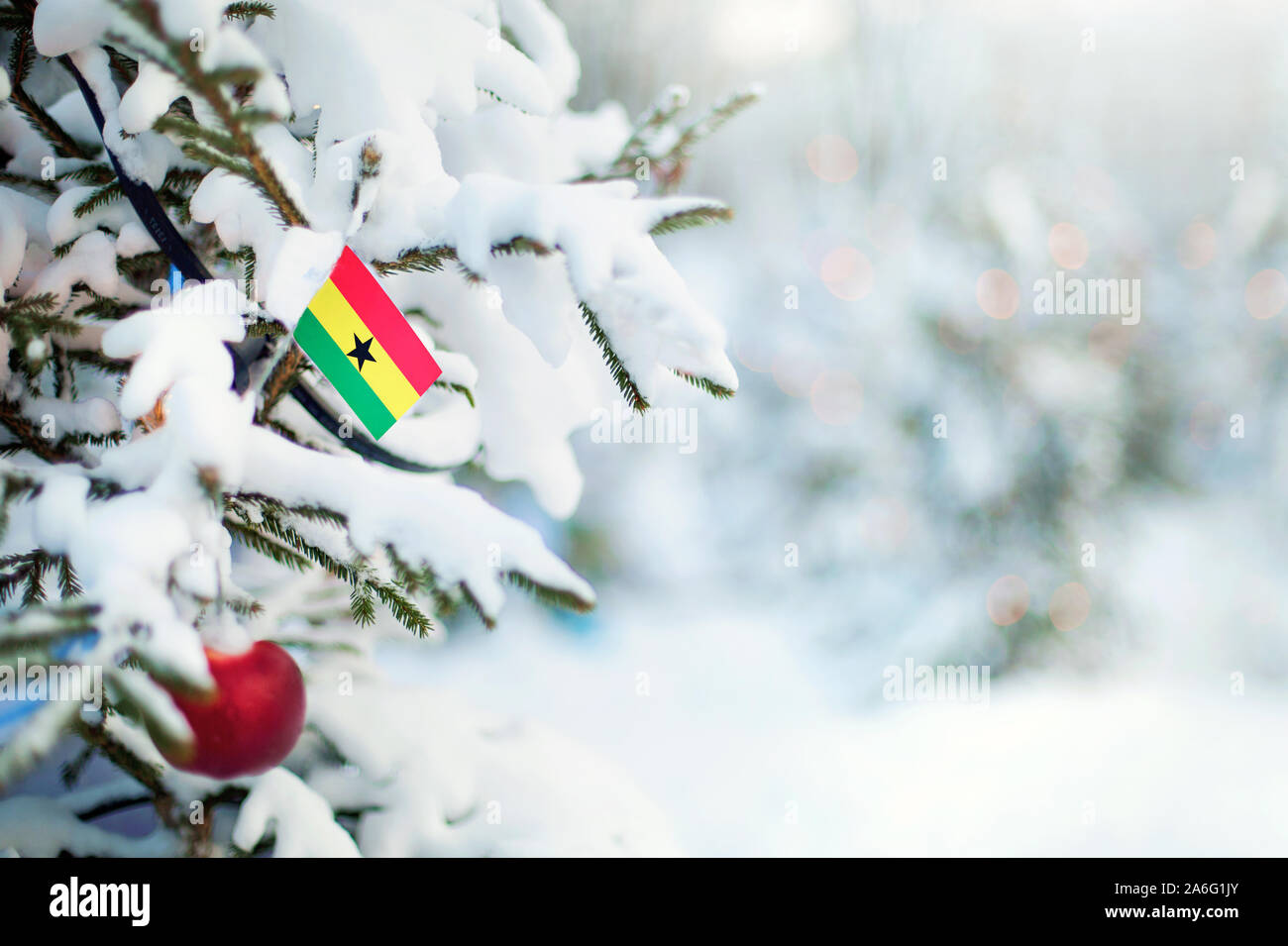 Christmas Ghana. Xmas tree covered with snow, decorations and a flag of Christmas Tree Gana