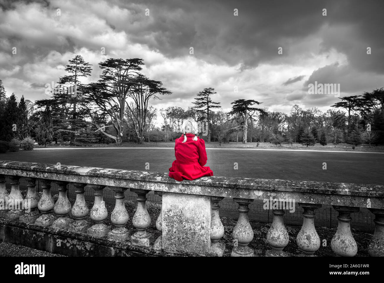 A little girl in a red coat looking at Ickworth house on a family day out, beautiful architecture and historic buildings, isolated, alone, thoughful Stock Photo