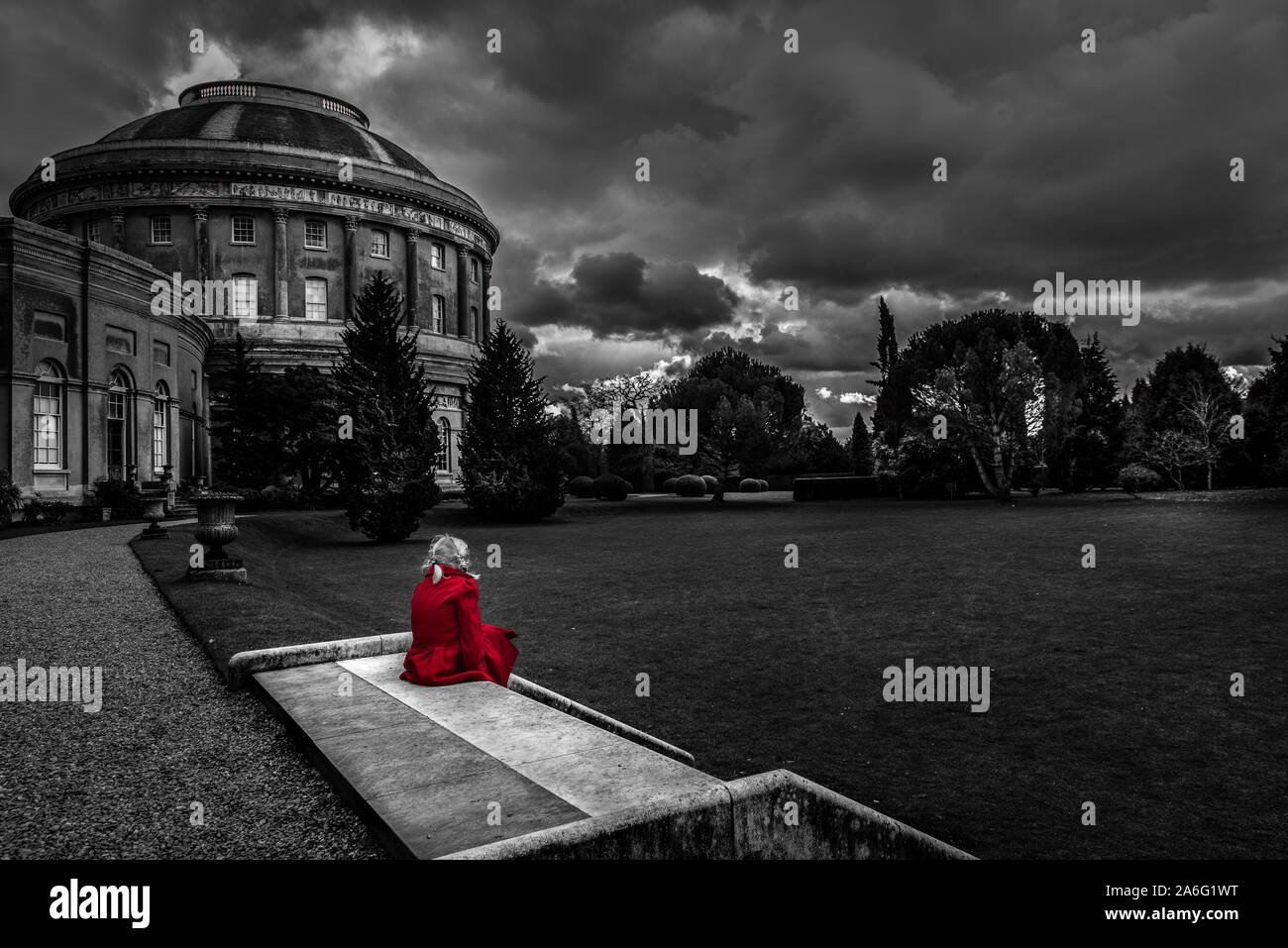 A little girl in a red coat looking at Ickworth house on a family day out, beautiful architecture and historic buildings, isolated, alone, thoughful Stock Photo