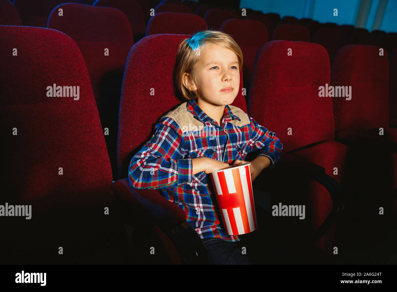 Little boy watching a film at a movie theater, house or cinema. Looks