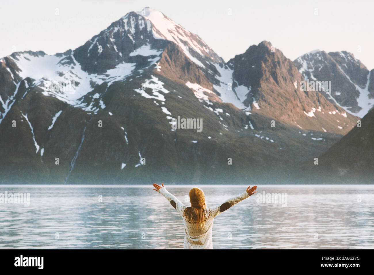 Traveler woman raised hands enjoying mountains Lyngen Alps view travel adventure vacations in Norway healthy lifestyle Stock Photo