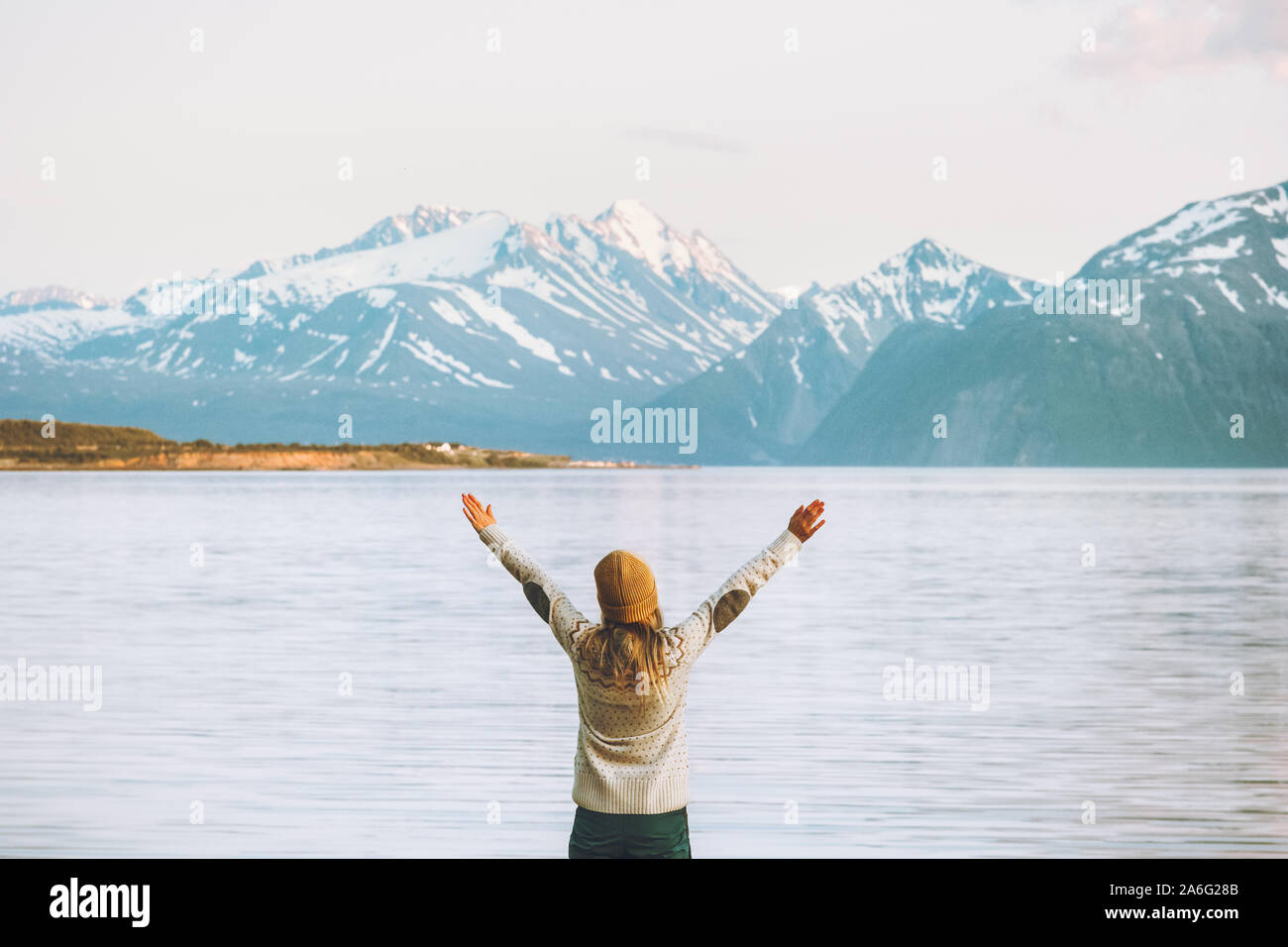 Happy woman hands raised traveling in Norway adventure vacations healthy lifestyle mountains Lyngen Alps and fjord landscape Stock Photo