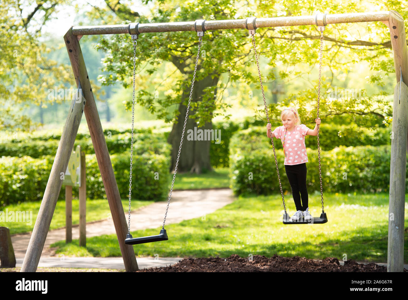 A pretty little girl playing at the park, climbing using the slide and swings enjoying being a child, Stock Photo