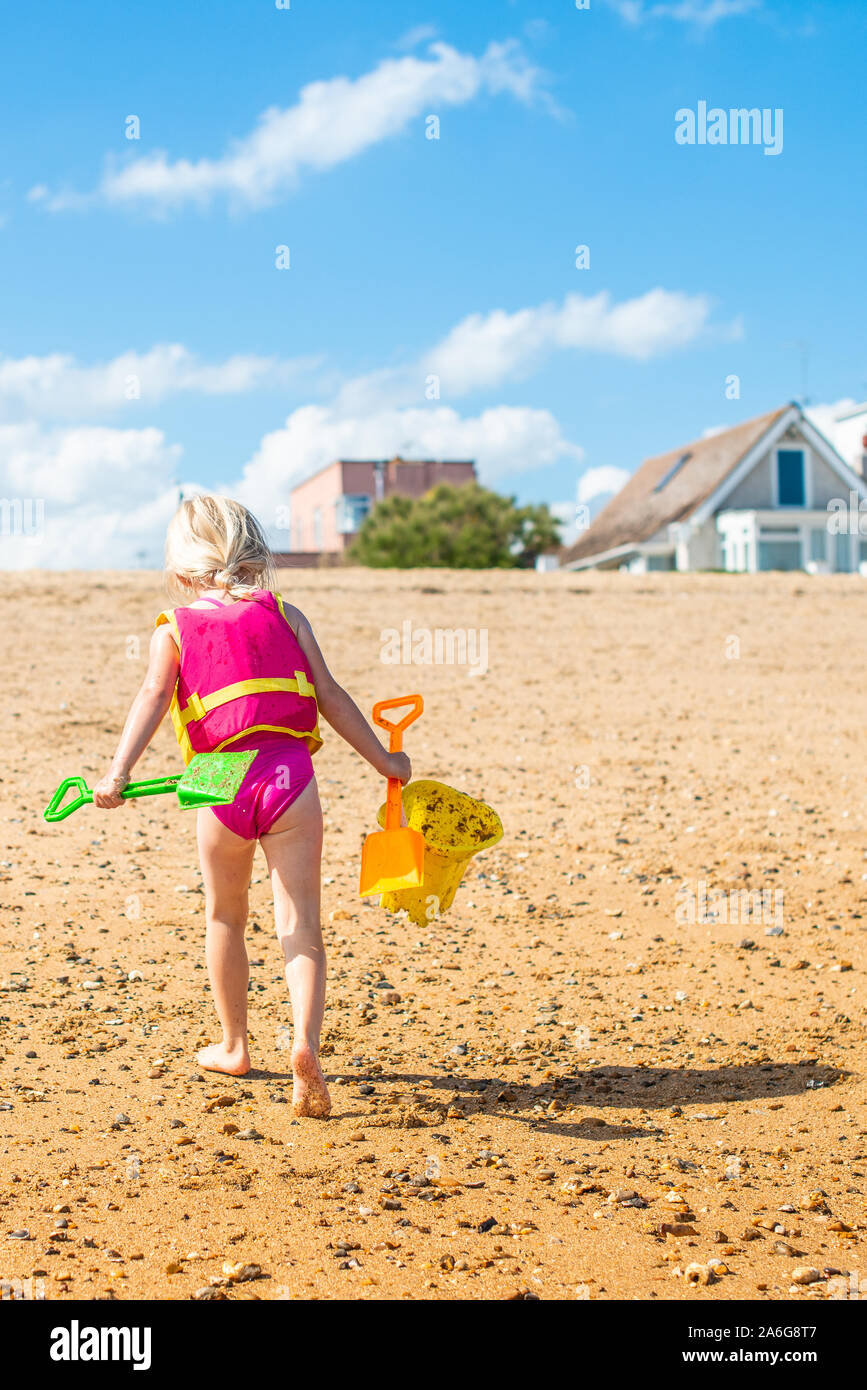 A little girl playing on the beach with buckets and spades making