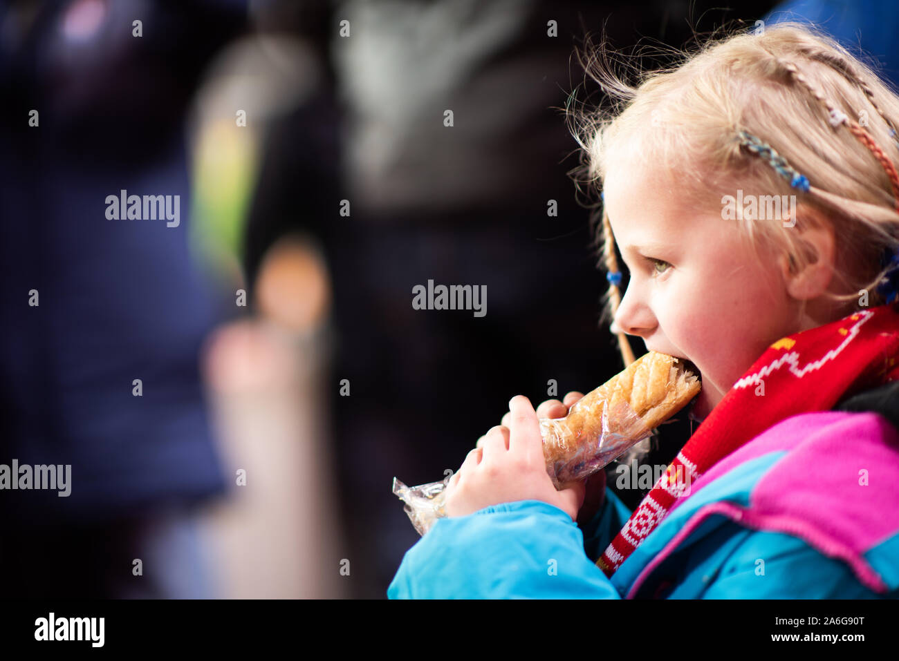 A pretty little girl enjoys a warm sausage roll at a Stoke City FC football match, BET 365 Stadium Stock Photo