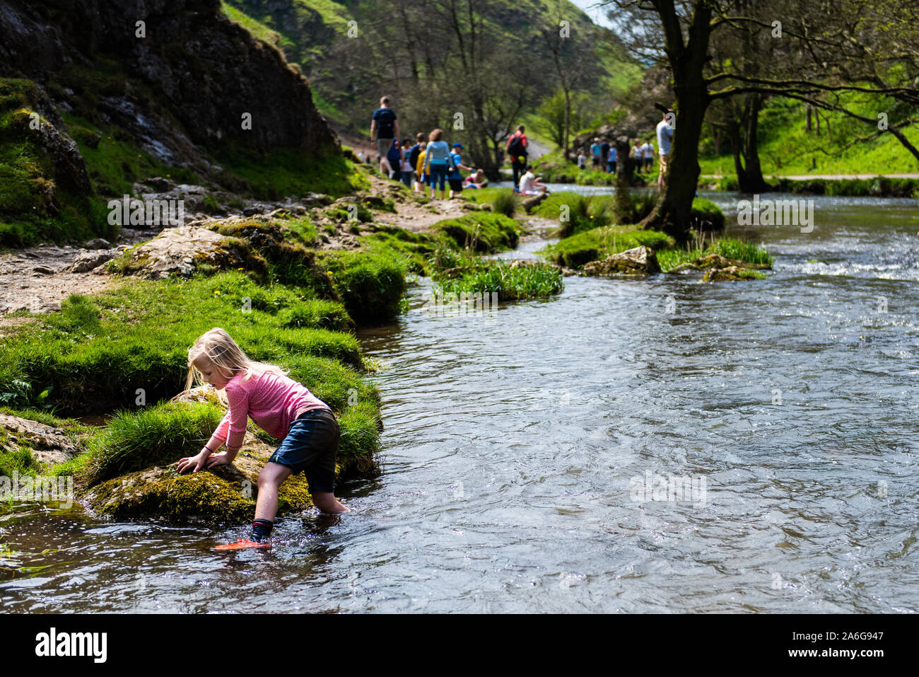 A pretty little girl paddling by the famous Dovedale stepping stones in the Derbyshire Peak District National Park Stock Photo