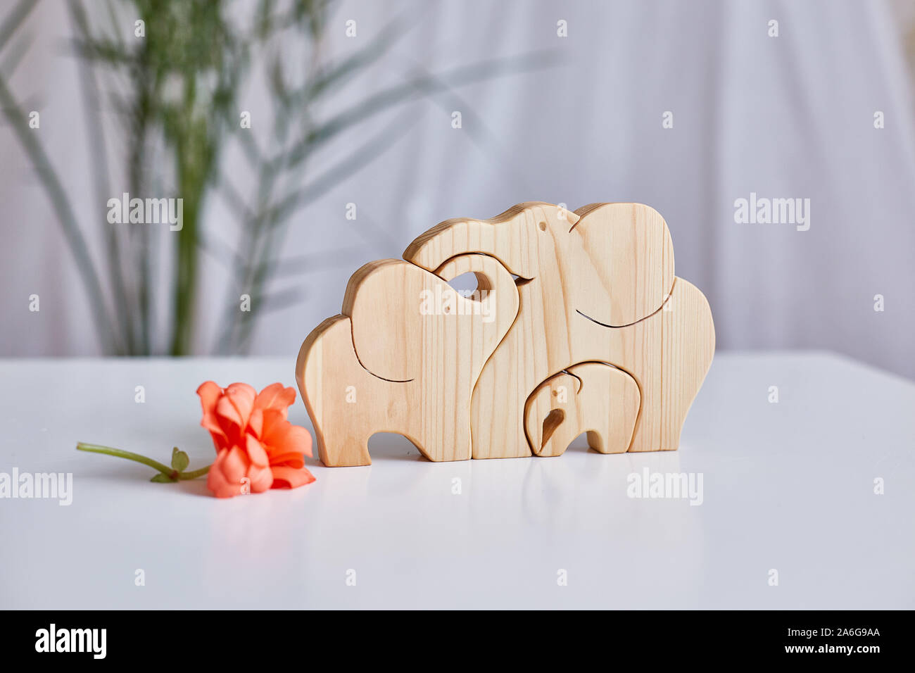 A family of elephants is carved from a light pine tree. traditional toys, a symbol of a happy family. shallow depth of field. Focus on elephants. Hori Stock Photo