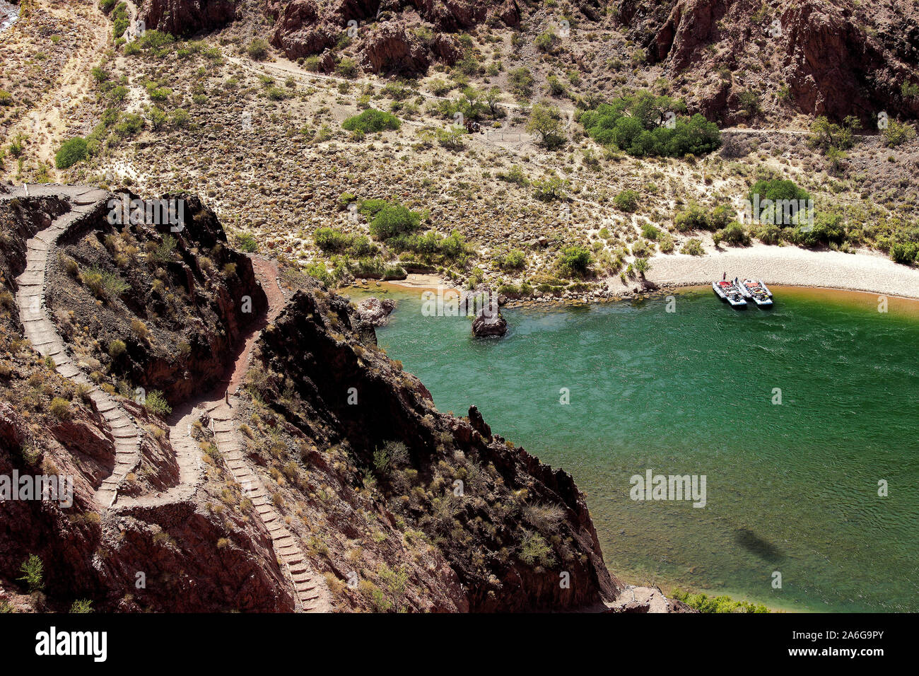 Twisting South Kaibab Trail in Grand Canyon with view of Colorado River and rafters just below docked at Boat Beach near Phantom Ranch Stock Photo