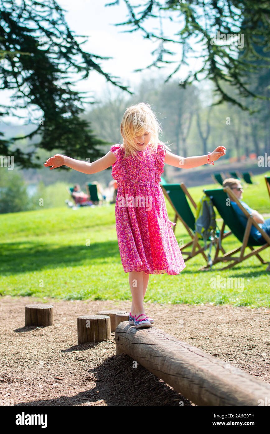 A cute, pretty little girl in a pretty pink dress skipping through a ...