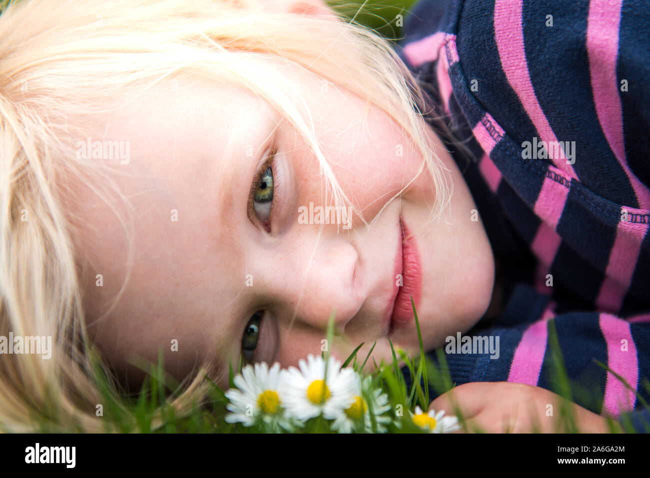 A Pretty Little Girl With Blonde Hair And Bright Green Eyes Lying