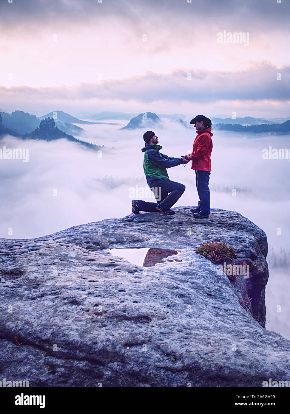 Silhouettes of hugging man and woman on mountain peak at misty sunset ...