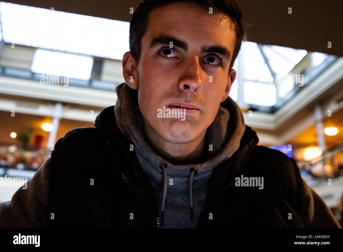 A young man waits at Stoke on Trent bus station for his bus, public transport, patience Stock