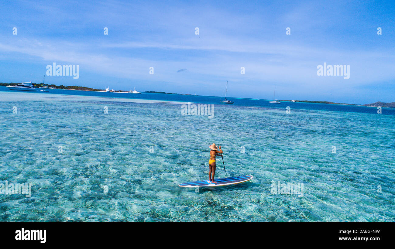 Aerial drone bird's eye view photo of young woman practising paddle board or sup in tropical Caribbean sapphire crystal clear calm waters Stock Photo