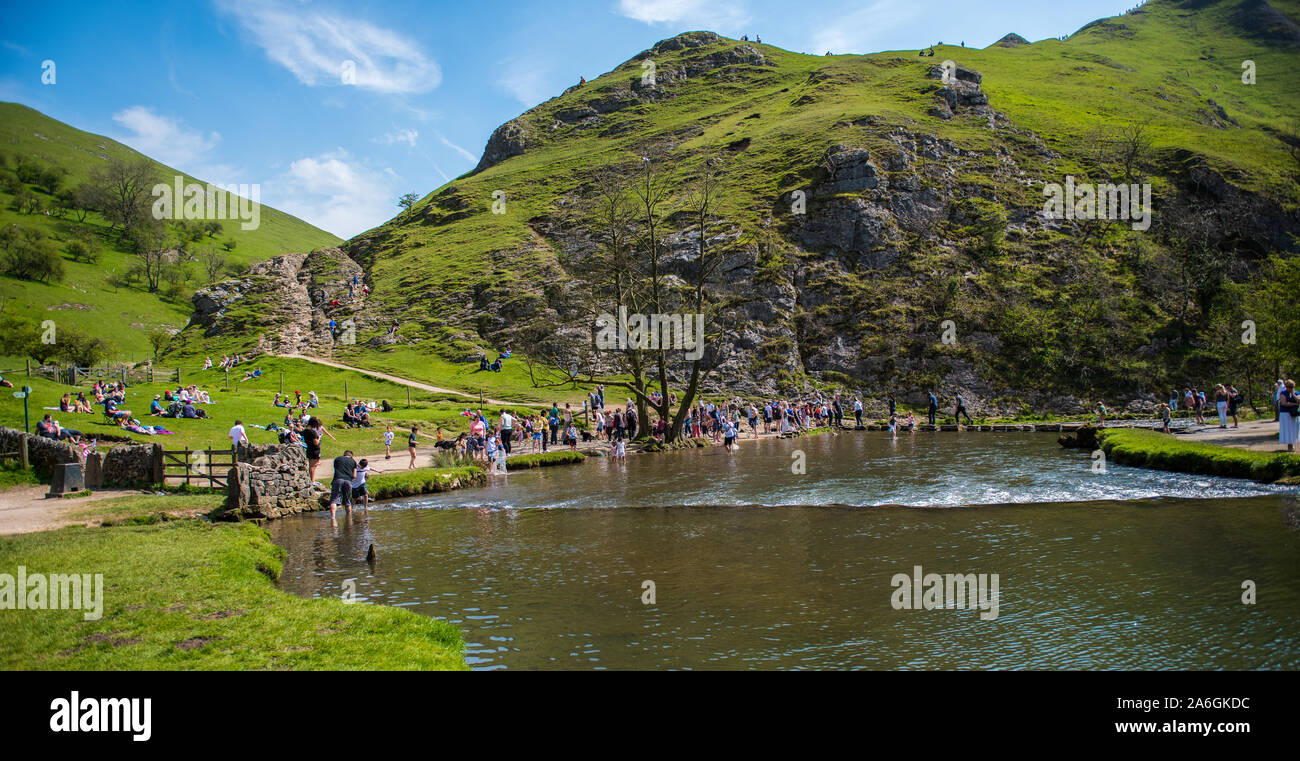 People enjoy a day out at the famous Dovedale stepping stones in the Peak District National Park Stock Photo